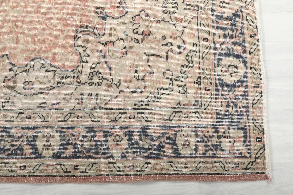 Detail view of the rug's navy and beige border with floral motifs and the rose field.