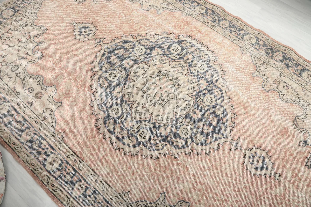 Overhead view of the rug's central navy medallion and the faded rose field with subtle patterns.