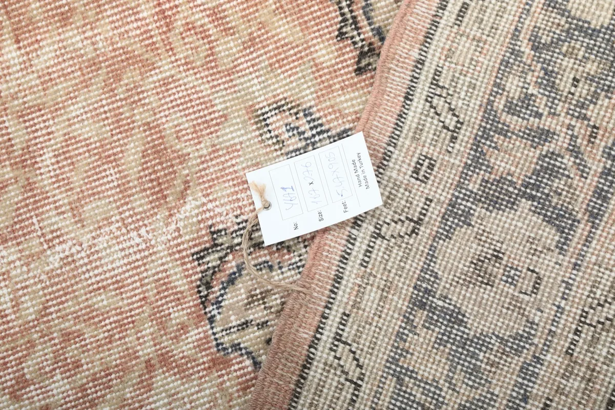 Detail of the rug's back with a product tag, displaying the hand-knotted construction.