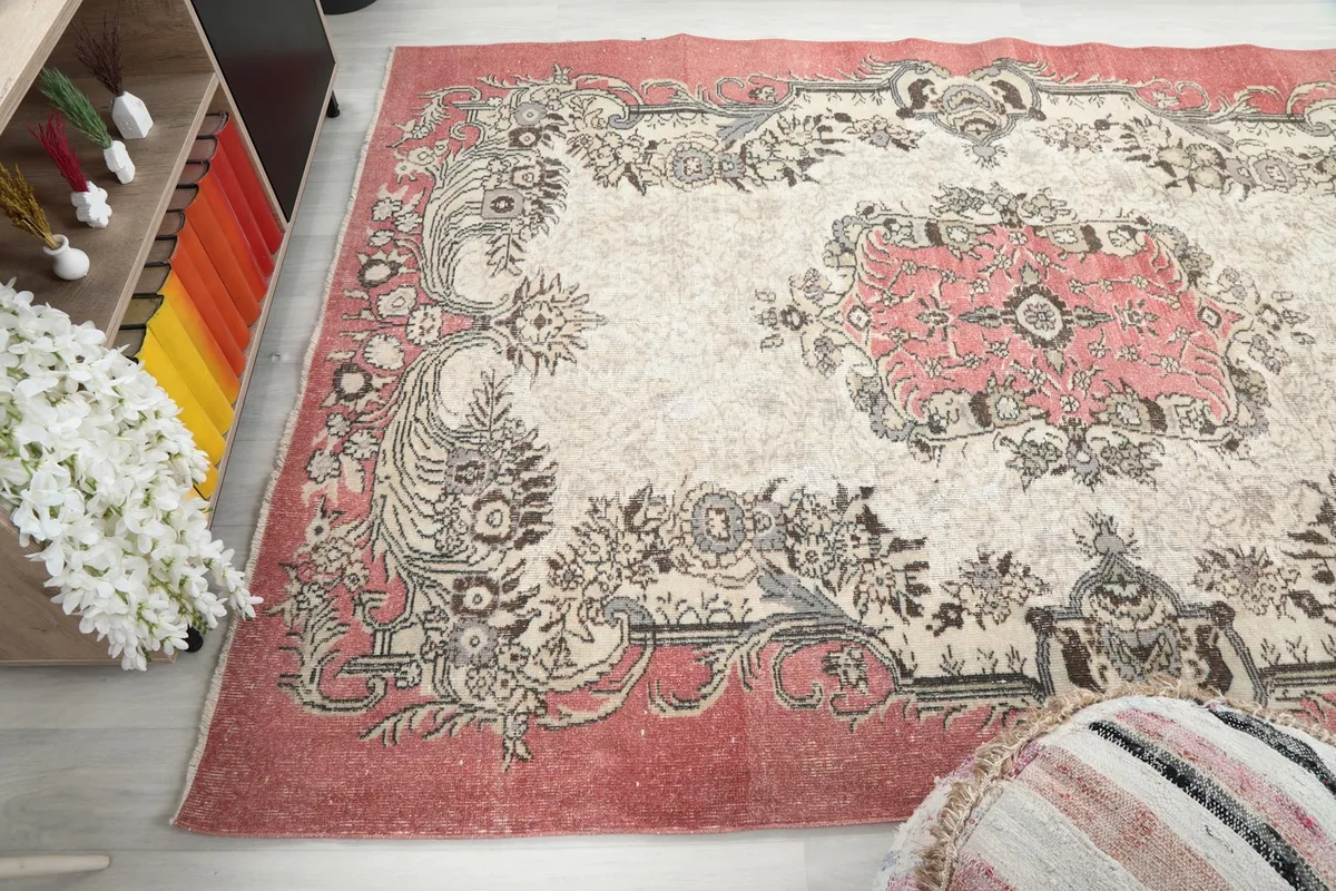 Angled shot highlighting the rose border and ivory field, with a pouf in the foreground