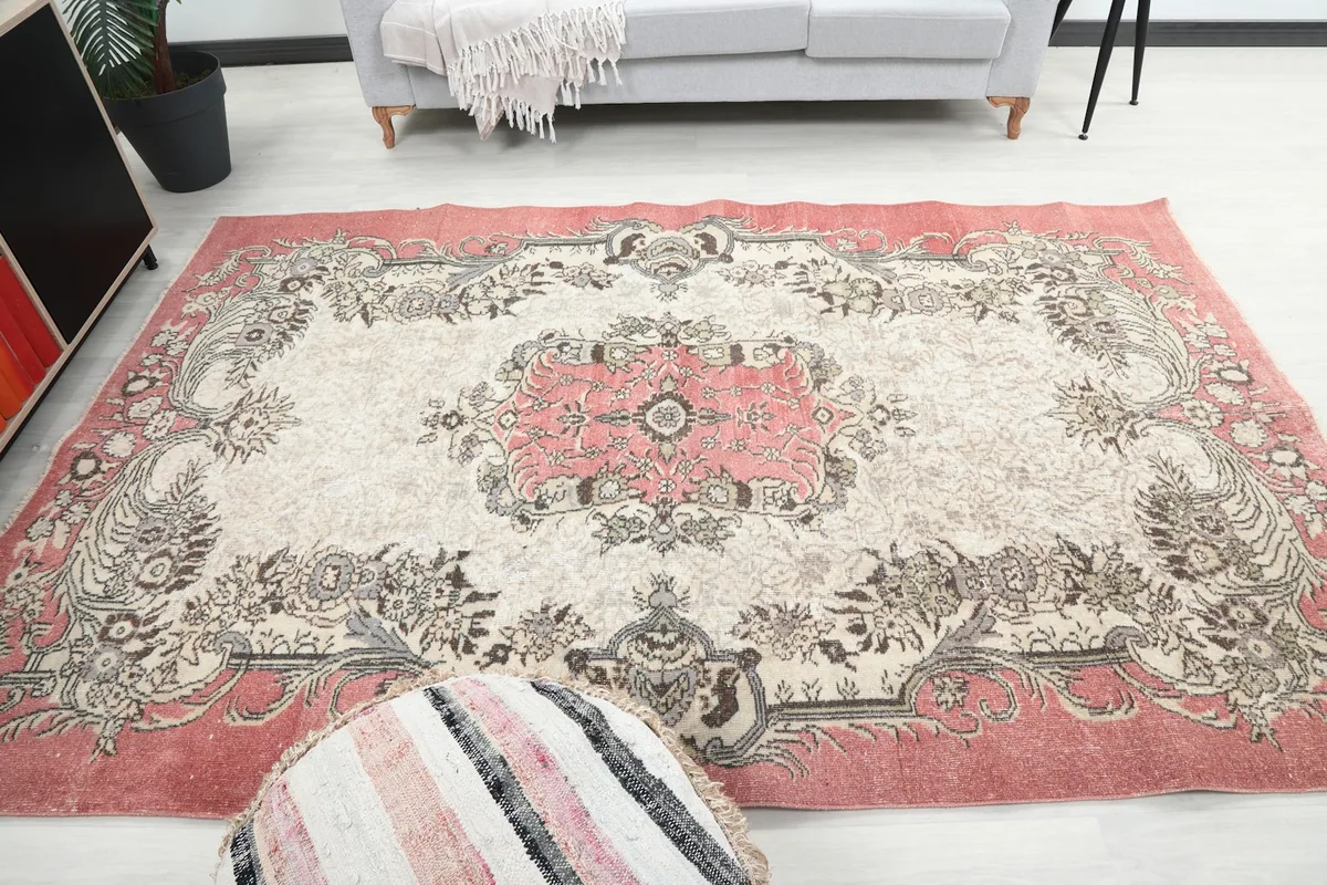 Full view of the rose and ivory rug laid out in a living room, seen from a higher angle