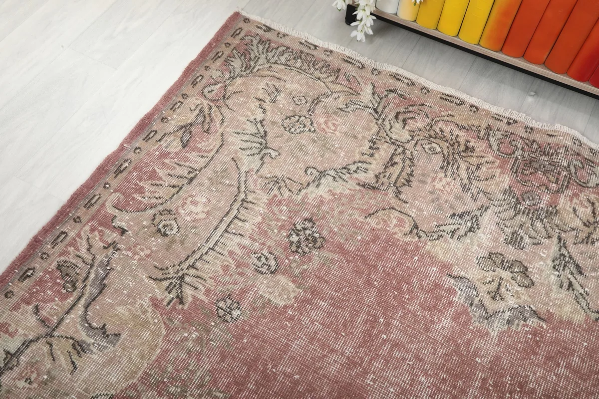 Angled view of the rug's upper section, displaying the faded rose field and motifs