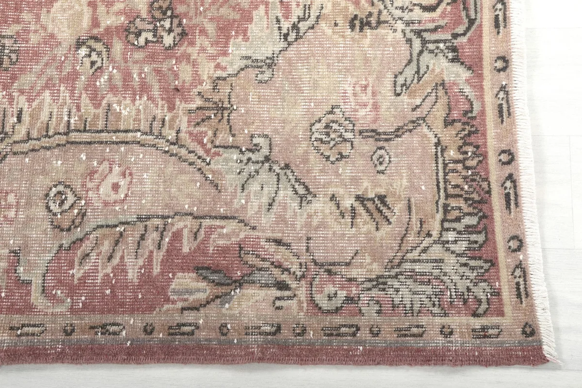 Close-up of the rug's border and corner showing faded rose and beige floral designs
