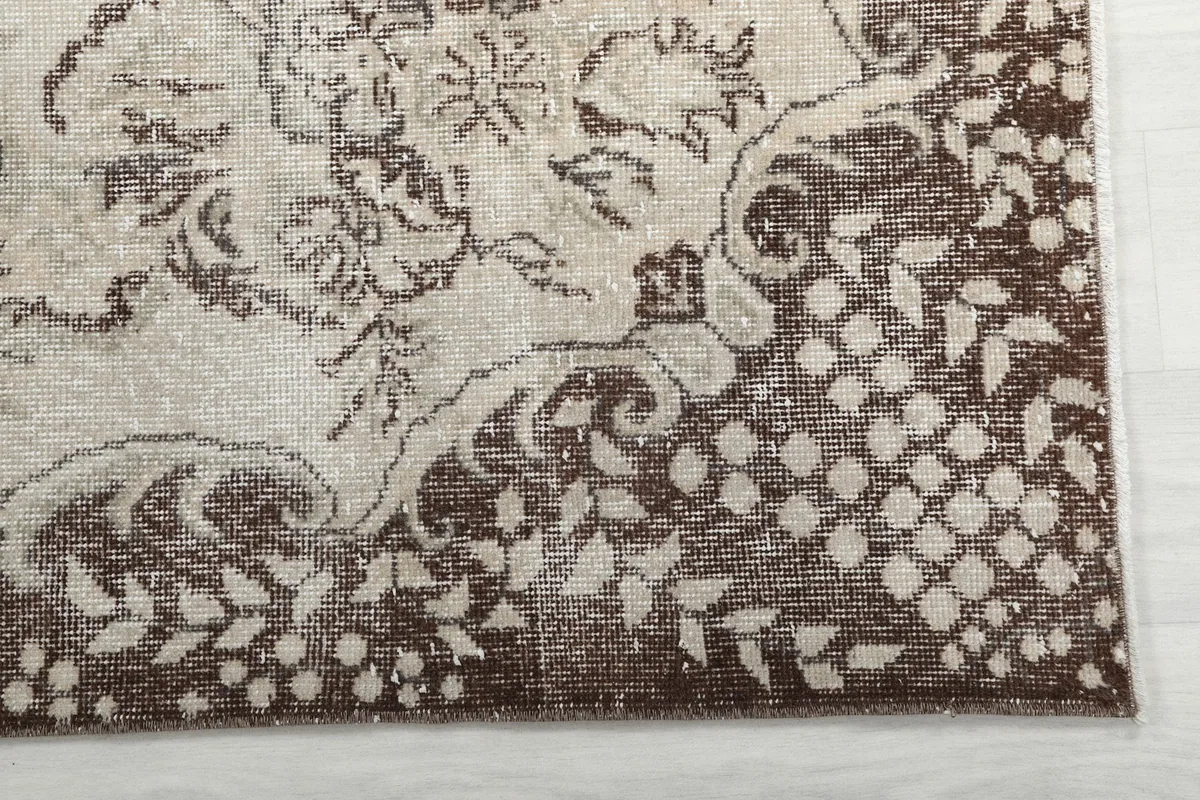 Detail of the rug's brown border pattern with floral and geometric elements