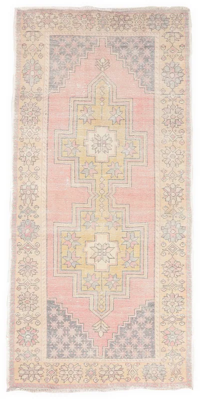 Full overhead view of the vintage pink and gold geometric Anatolian rug on a white background