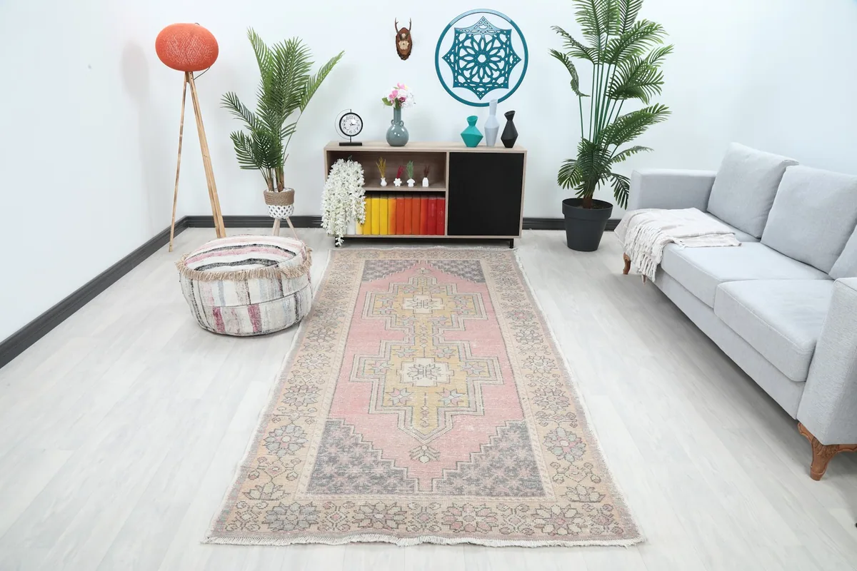 Vintage pink and gold geometric rug displayed in a living room setting with a gray sofa
