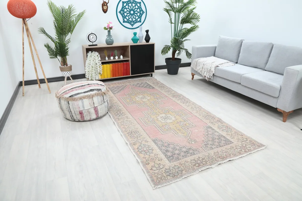 Angled view of the pink and gold Anatolian rug in a modern living space with light flooring
