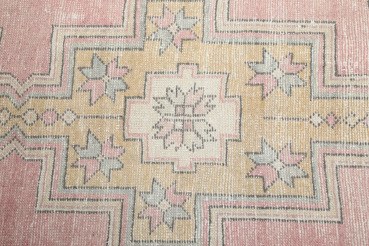Close-up of the central geometric medallion with intricate details in gold, pink, and gray tones