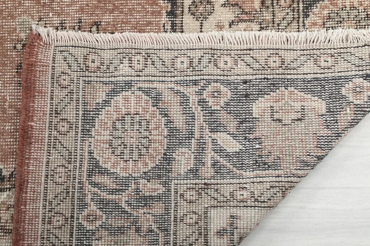 Close-up of the rug's reverse side, showing the hand-knotted construction and fringe