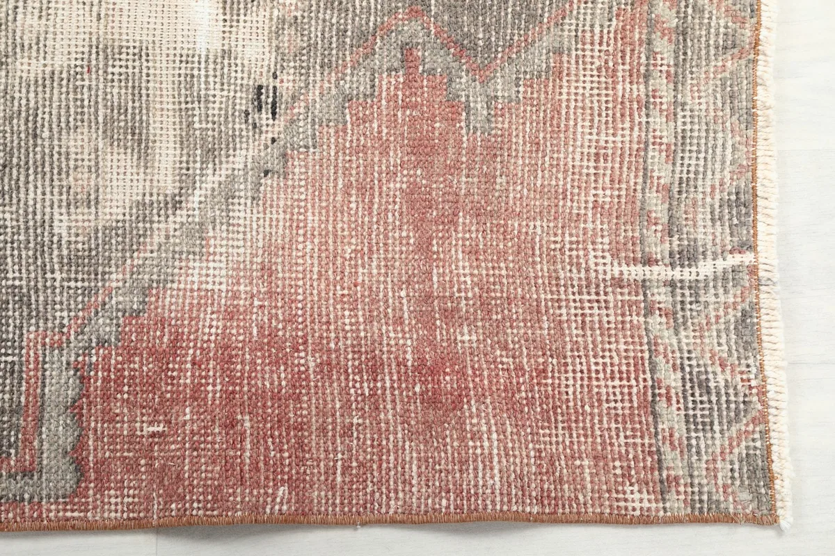 Close-up of a corner of the runner rug, highlighting the distressed wool pile and color variations