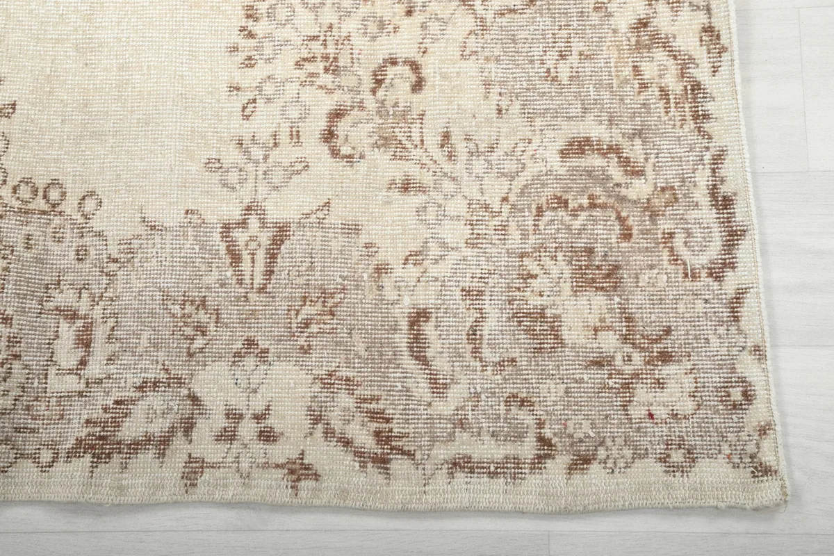 Detailed view of the intricate tan floral border design on the vintage rug
