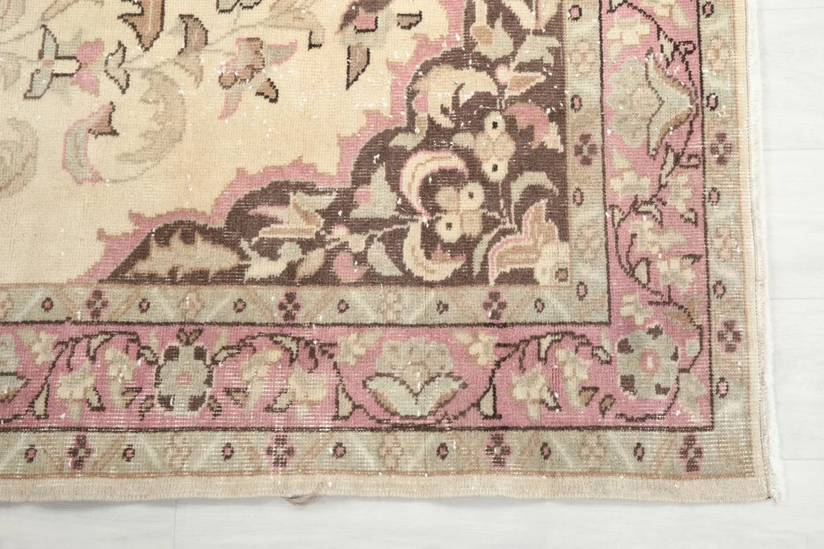Detail of the corner and border design, highlighting pink and brown tones on the ivory field