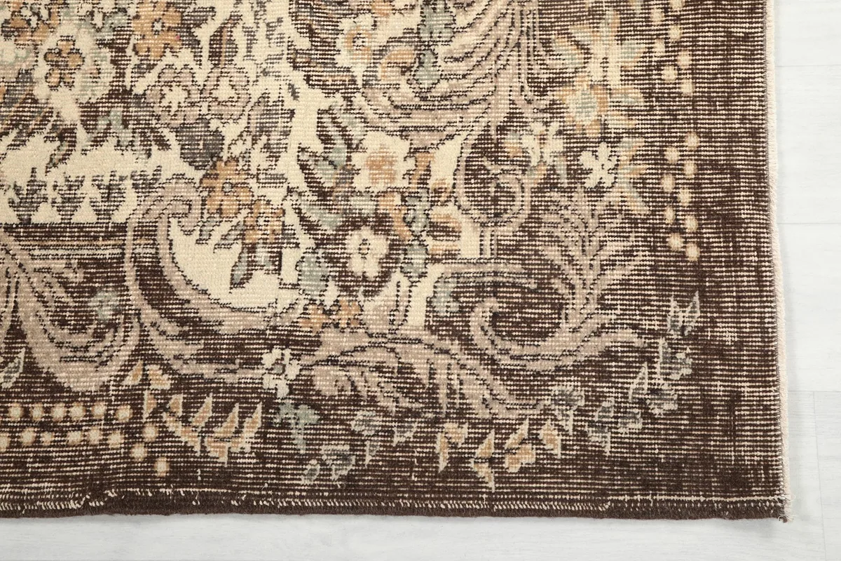 Detailed view of the brown border and corner design on the vintage wool rug