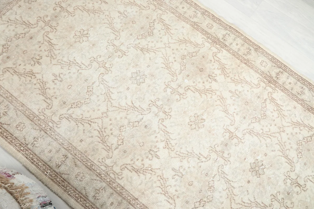 Overhead angle capturing the full length of the ivory rug and its repeating floral design