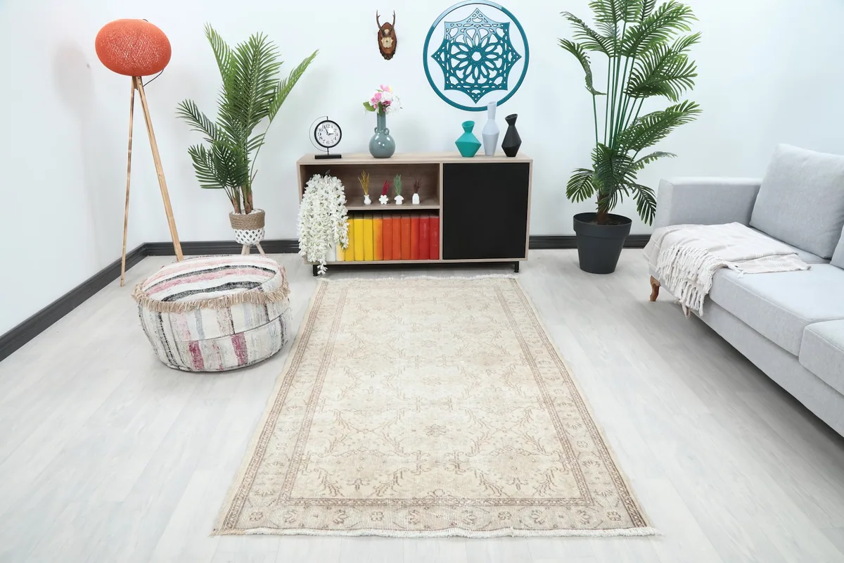 Ivory vintage rug placed in a modern living room setting with plants and a sofa