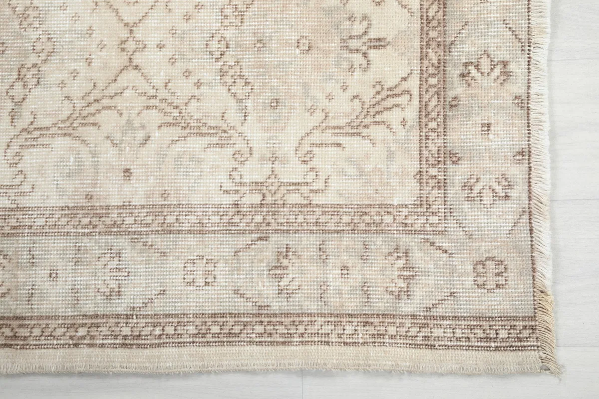 Detailed view of the rug's corner, highlighting the beige border and floral motifs