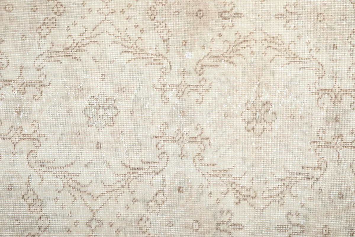 Close-up of the rug's field, revealing the hand-knotted texture and faded beige patterns