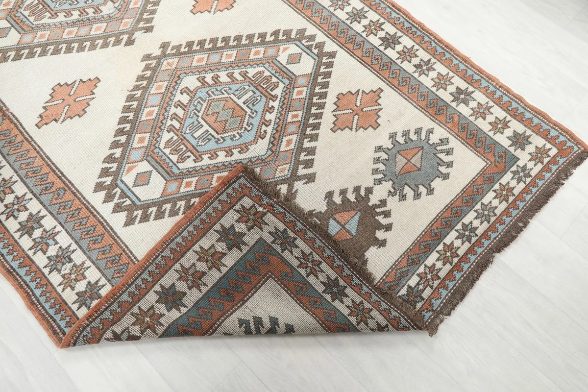 Corner of the rug folded back, revealing the hand-knotted cotton foundation.