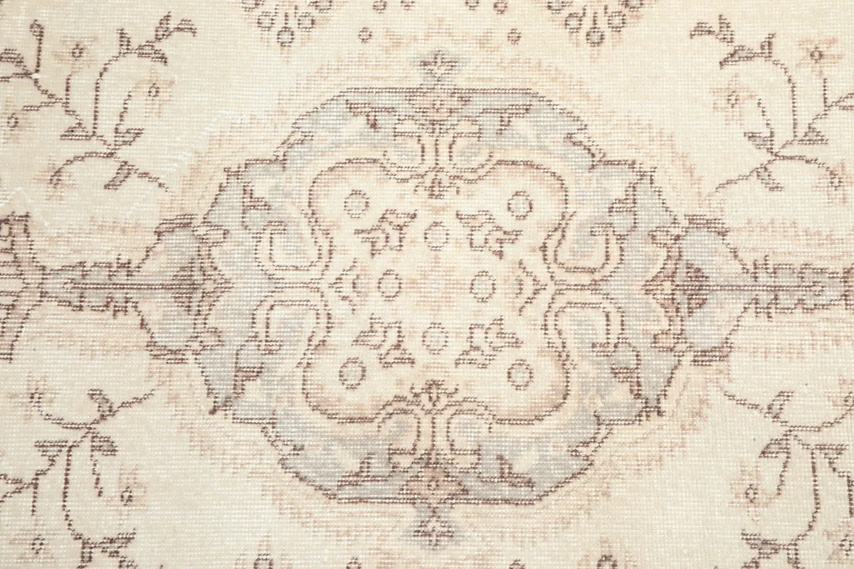 Close-up of the rug's central medallion with ivory, rose, and gray tones