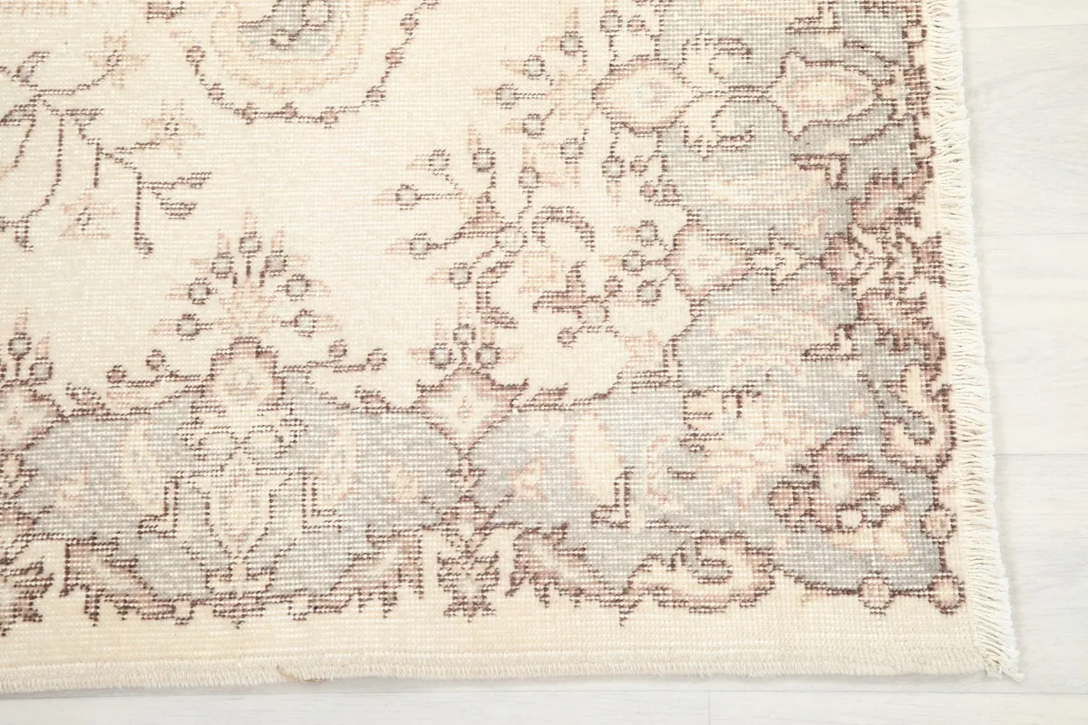 Close-up of the rug's corner showing the rose and gray floral border pattern