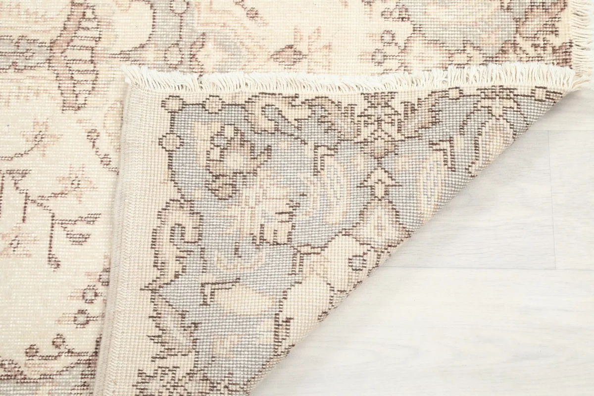 Flipped corner of the rug revealing the hand-knotted cotton foundation
