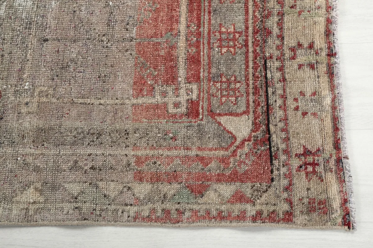 Detailed view of the rust-colored medallion and geometric border patterns at one end of the rug.