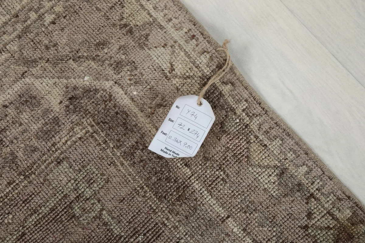 Close-up of the rug's surface with an attached product tag, showing the texture and faded colors.