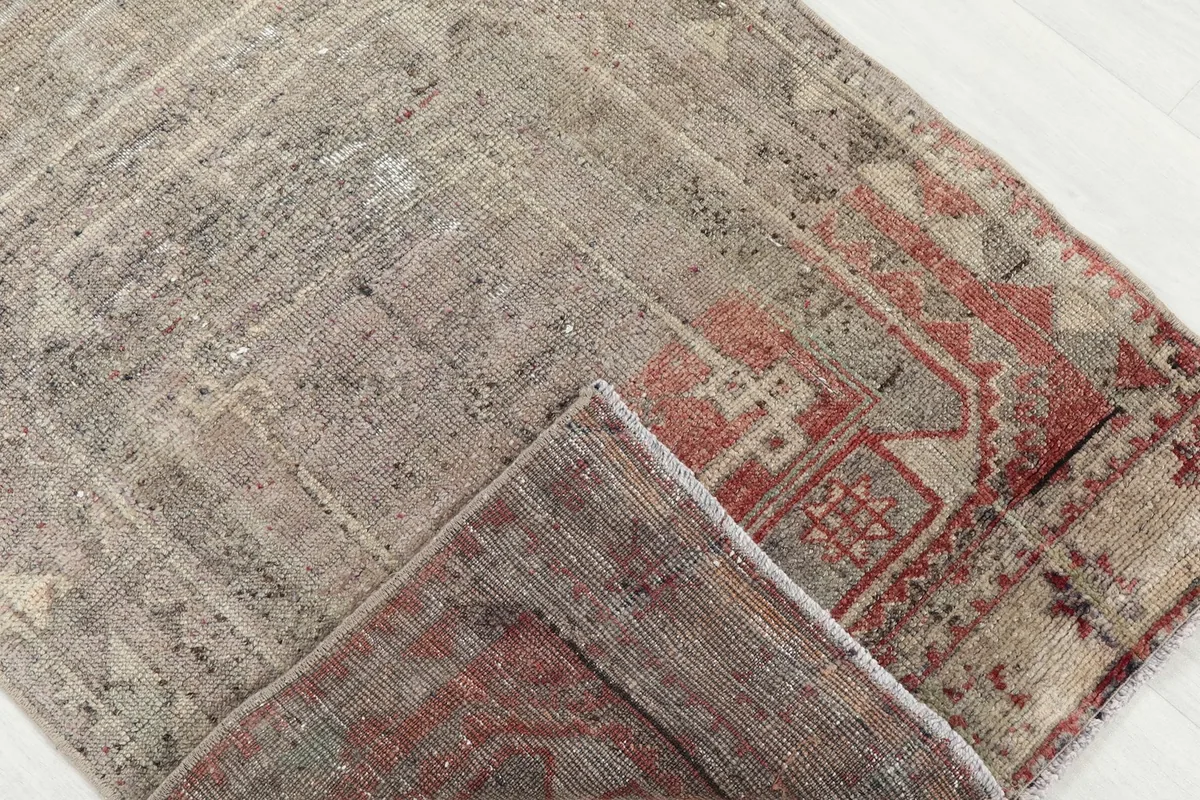Folded corner of the rug, showing the wool pile and cotton foundation, with rust and gray details.