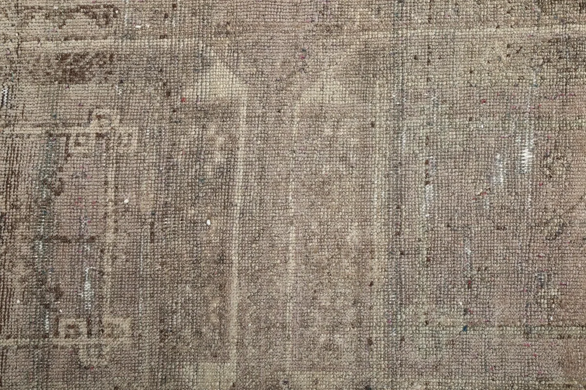Direct overhead shot of the rug's central field, revealing faded geometric designs and wear.
