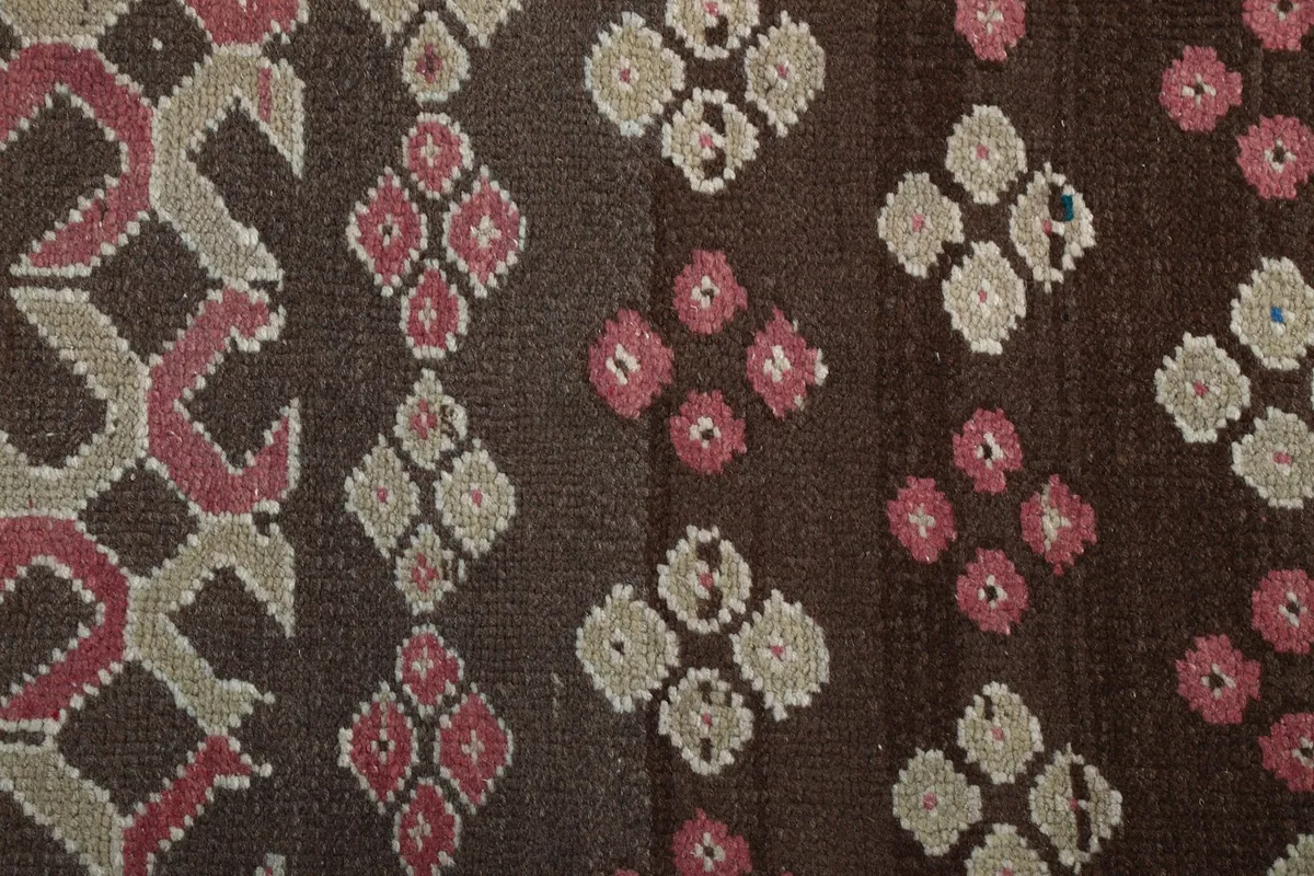 Close-up of the hand-knotted wool pile, revealing the texture and subtle color variations within the pink and beige motifs.