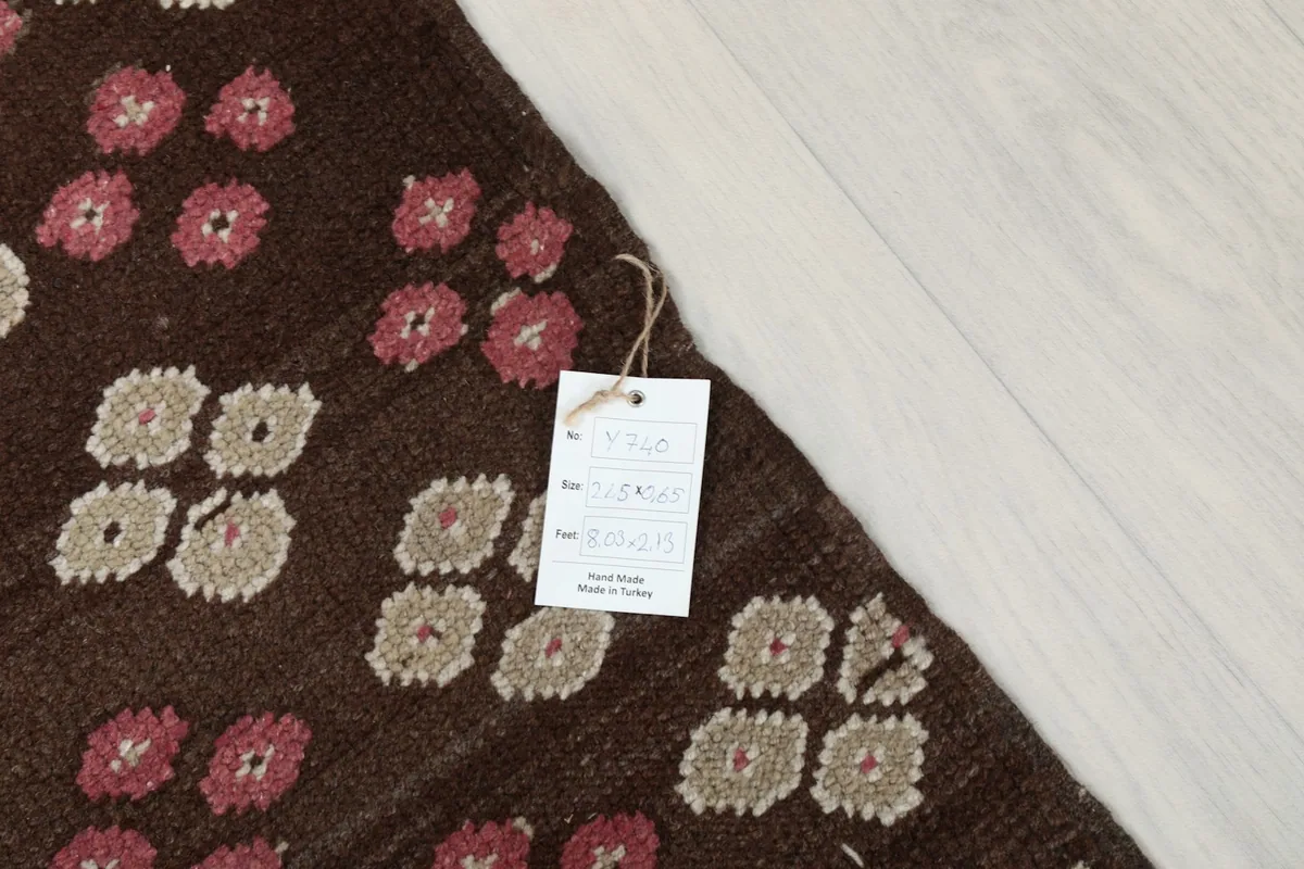 Detail of the rug's surface with an attached product tag, showing the wool pile and patterns.