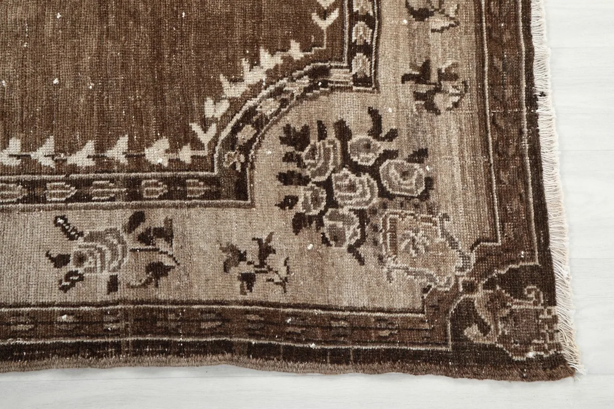 Detailed view of the corner of the rug, showing floral motifs in beige and brown