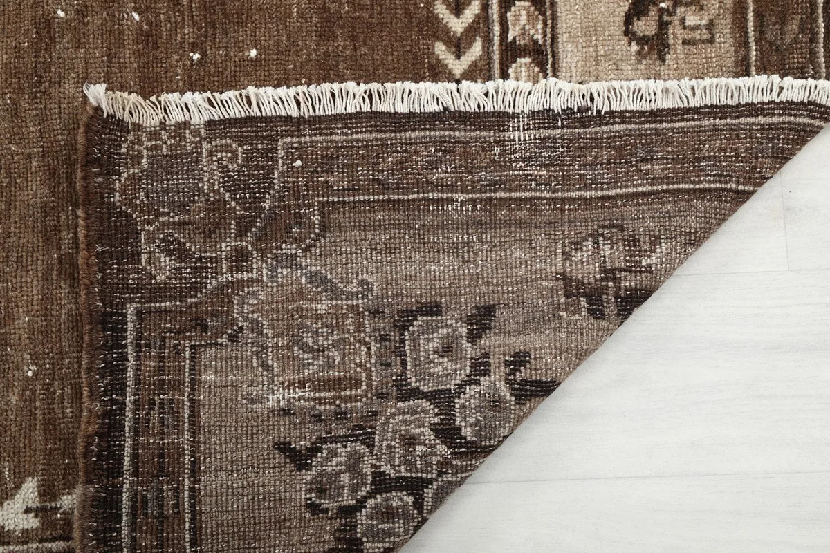 Close-up of the rug's pile and fringe, showing the wool texture and wear
