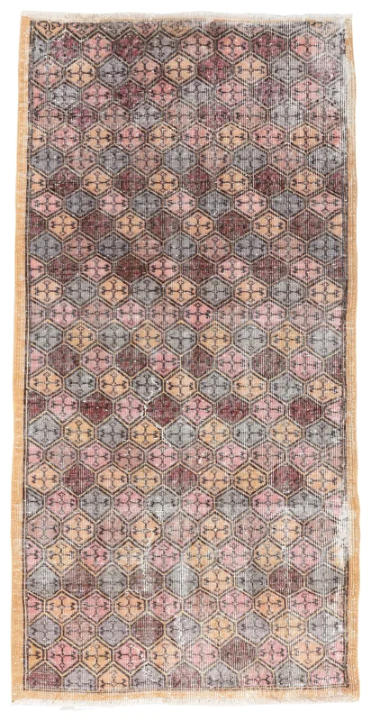 Full overhead view of the vintage pink, gray, rust, and tan geometric Anatolian rug on a white background.