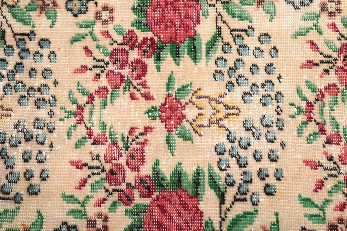 Close-up detail of the hand-knotted wool pile, showing individual floral motifs and color variations.