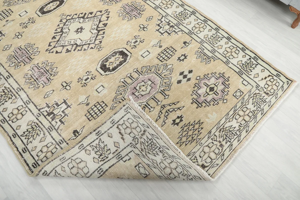 Corner of the Beige Tribal Geometric Rug folded back, revealing the reverse side and knotting.