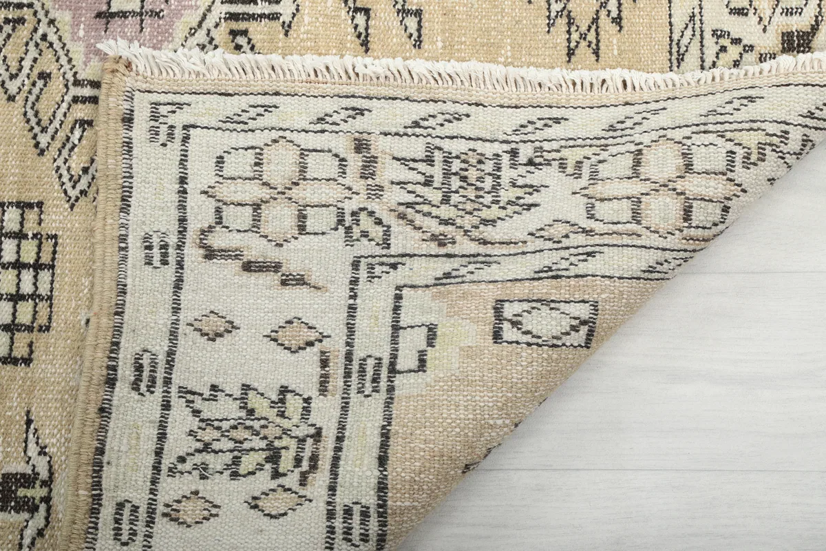 Detail of the folded corner of the Beige Tribal Geometric Rug, showing the back of the rug.