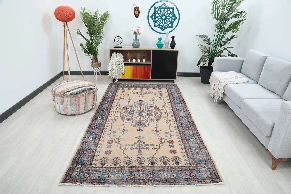 Vintage Anatolian rug with cream field and blue border displayed in a modern living room setting