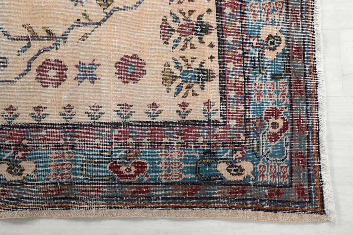 Detailed view of the rug's corner, highlighting the blue and rose border patterns and low pile