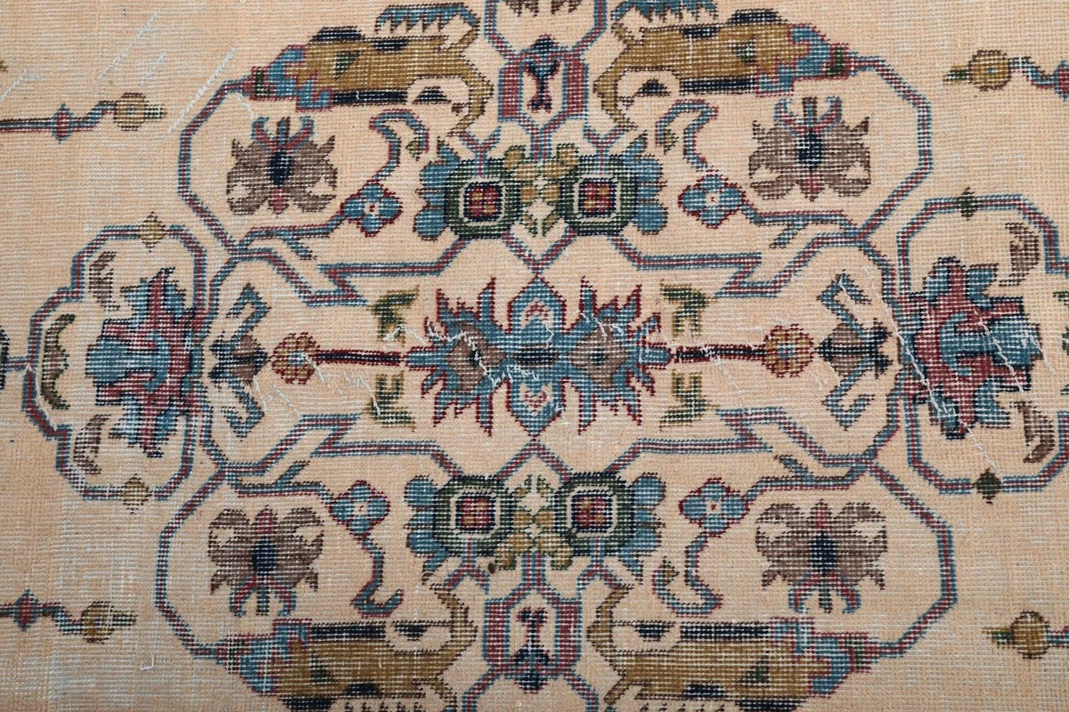 Close-up of the central medallion with blue, rose, and green motifs on the cream field