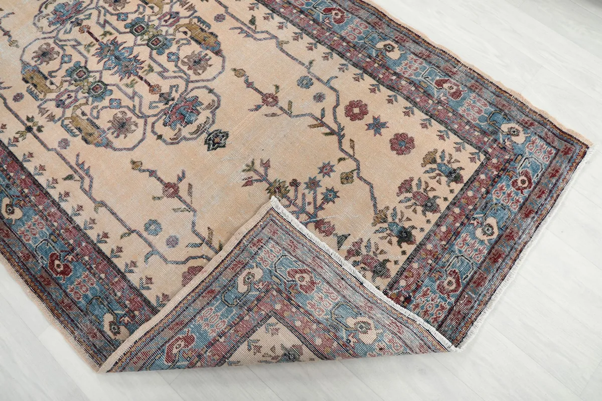 Corner of the rug folded back, revealing the wool pile and cotton foundation construction
