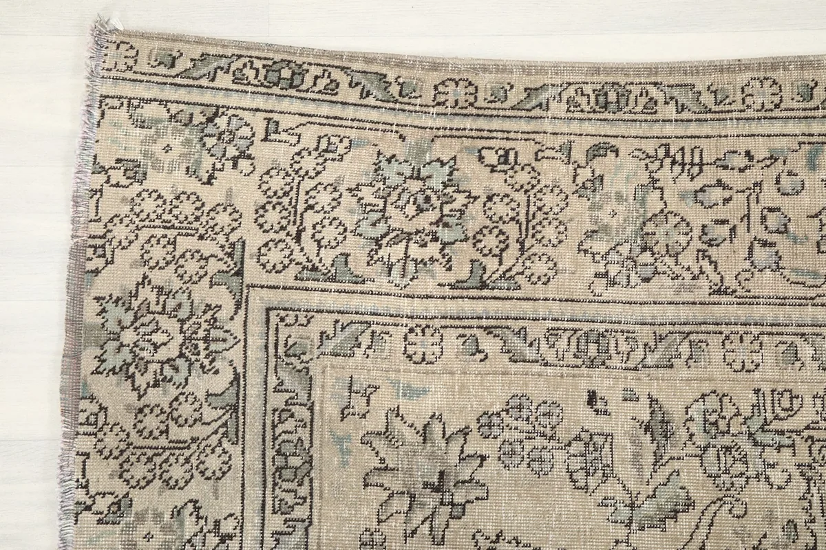 Detail of the rug's corner, highlighting the floral border and subtle blue accents