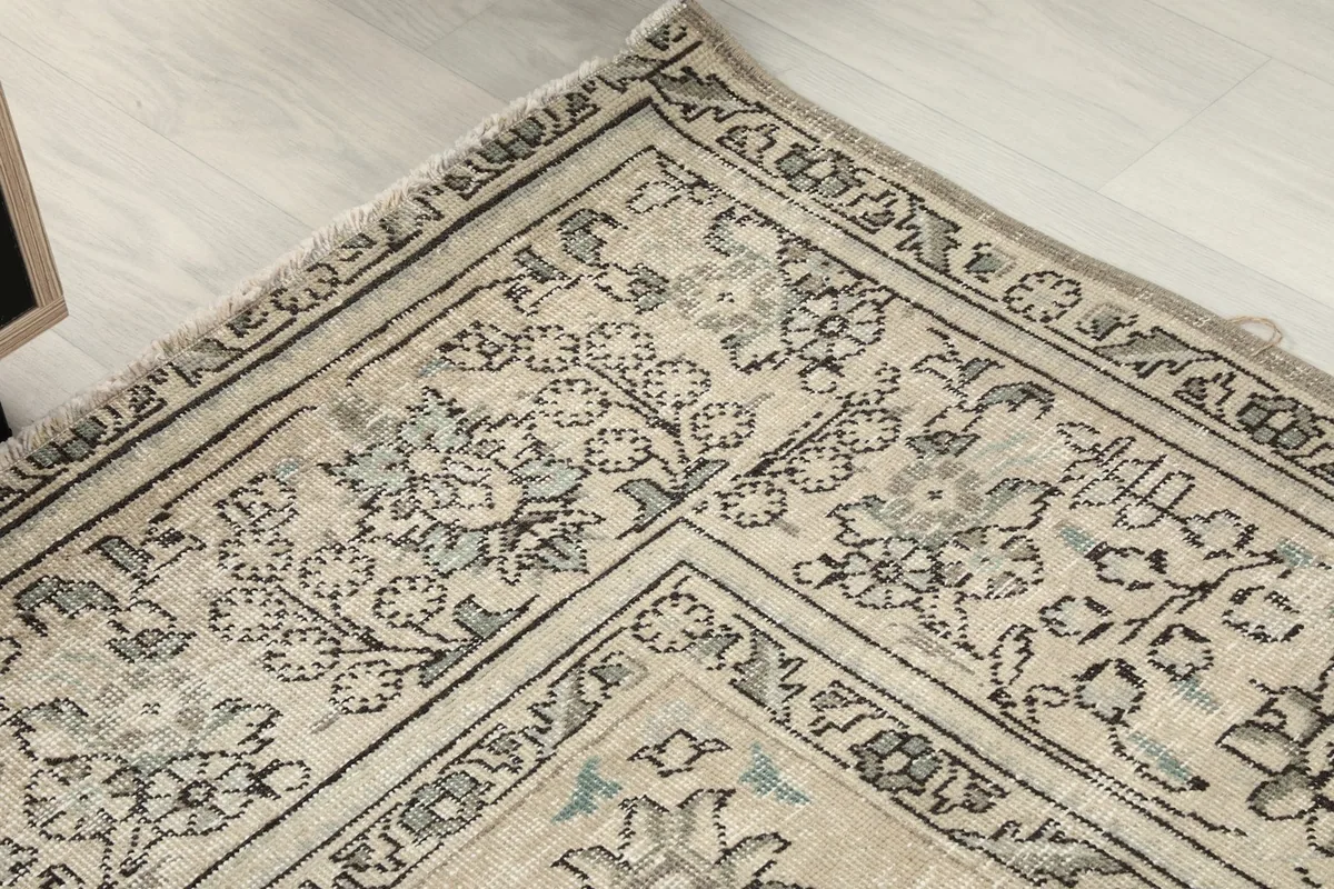 Detailed shot of the rug's border, showing the floral motifs and slight wear