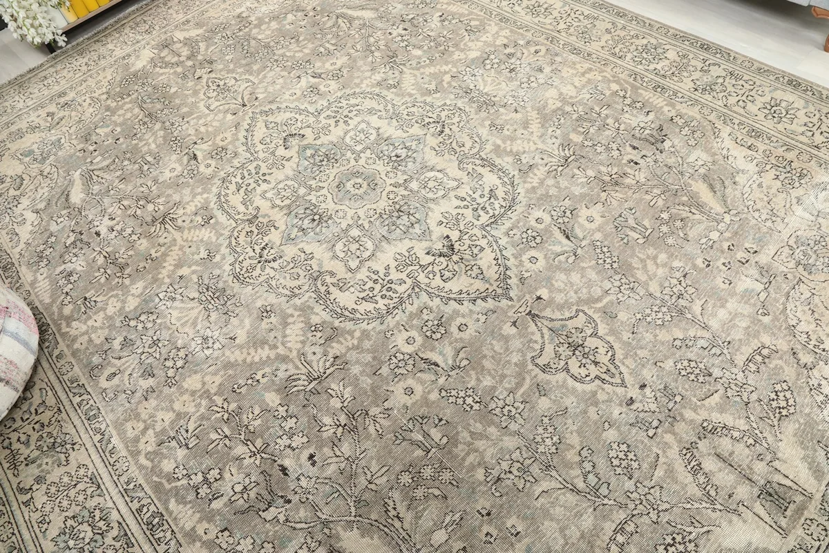 Overhead view of the vintage rug, emphasizing its faded gray and beige field