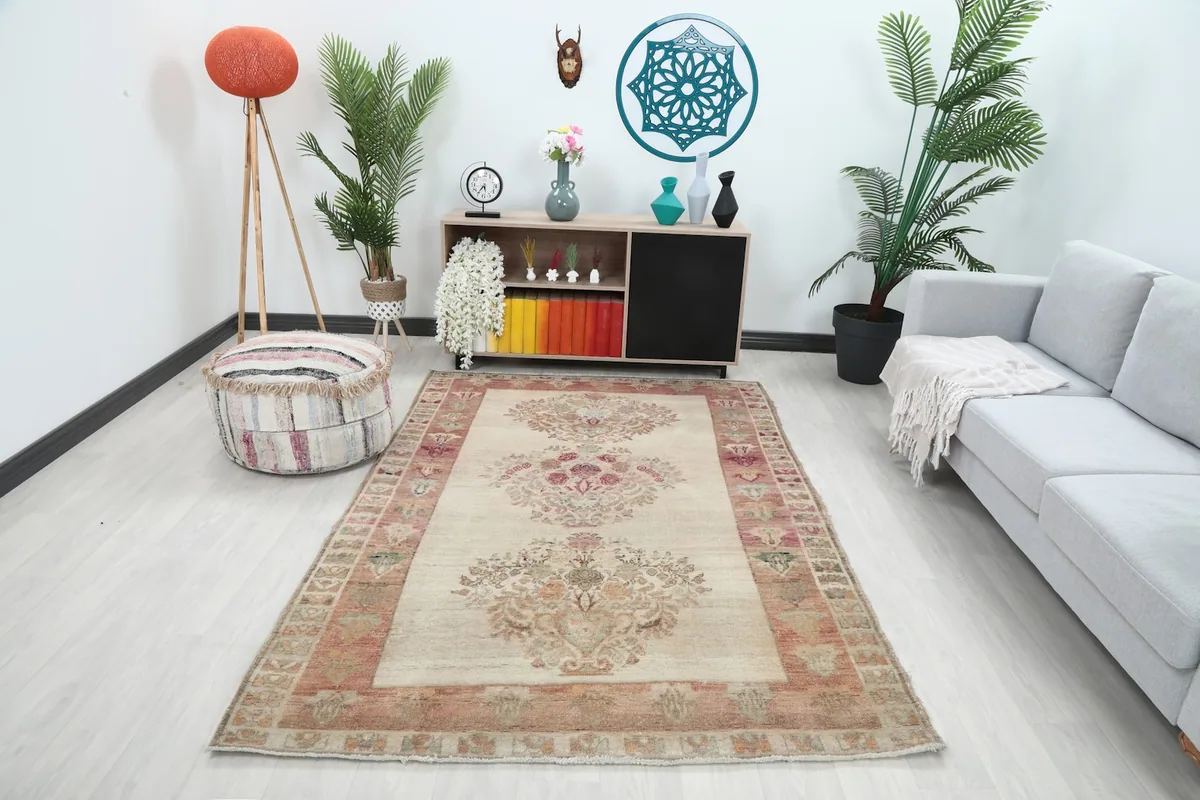 Ivory and rose floral rug displayed in a living room setting with a sofa and cabinet