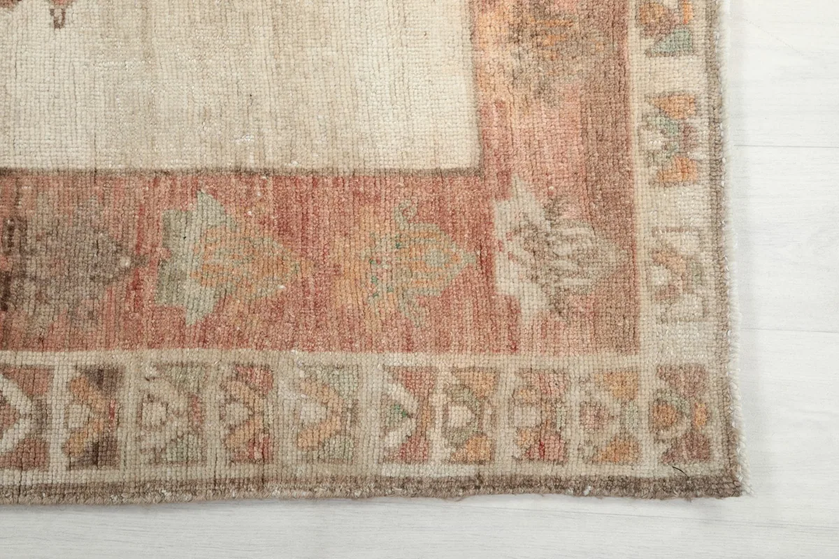 Detail view of the rug's rust-toned border with geometric patterns and corner design