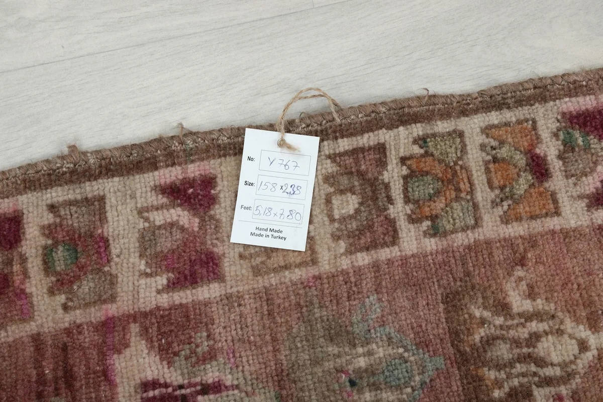 Care tag attached to the rug's edge, indicating its hand-knotted origin and material