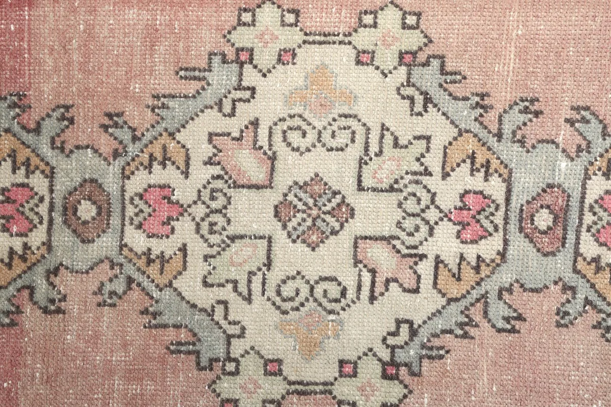 Close-up of a single geometric medallion with ivory, gray, and pink details