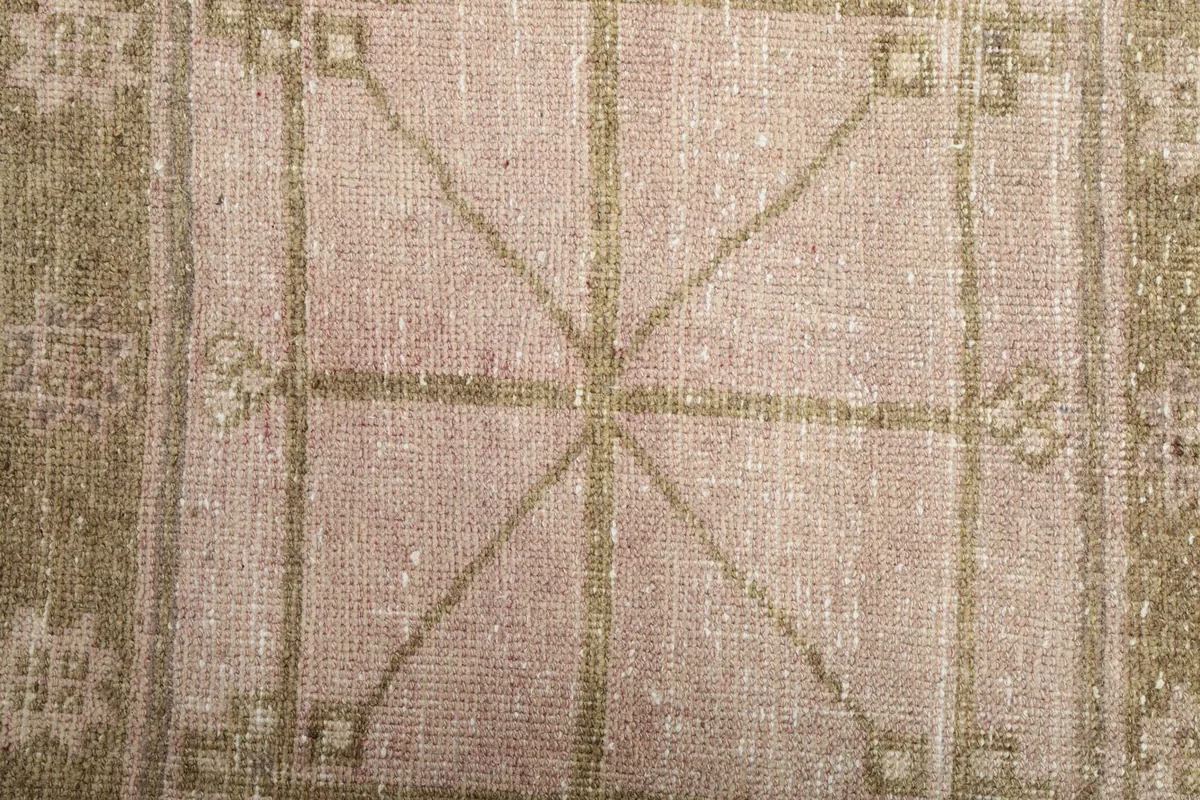 Close-up of the central cross motif within a geometric square, highlighting the hand-knotted wool pile.
