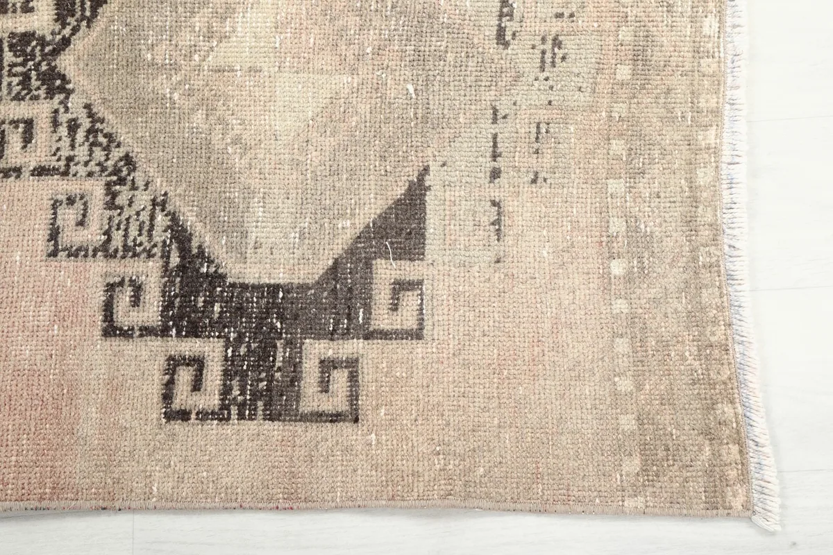 Detailed view of the charcoal geometric pattern and the edge of the rug, revealing the hand-knotted texture.